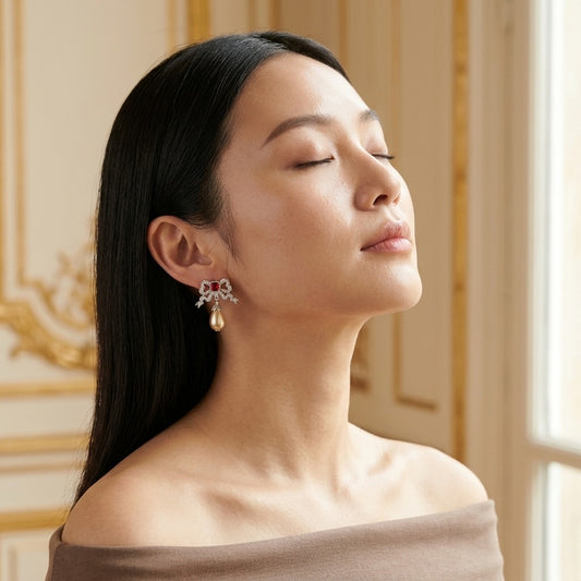 Model wearing the Nœud Rouge Drop Earrings, silver-tone brass, simulated rubies, simulated pearls, simulated diamonds